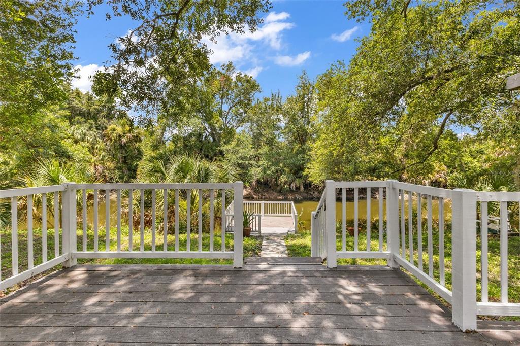 A wooden deck with white railings overlooks a small dock on a river — 297 FLAMINGO BOULEVARD, PORT CHARLOTTE, FL
