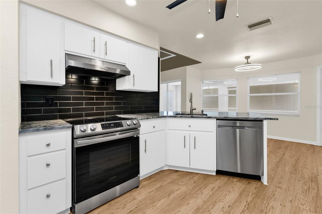 A screened-in patio with dark tile flooring overlooks a grassy yard with trees — 297 FLAMINGO BOULEVARD, PORT CHARLOTTE, FL