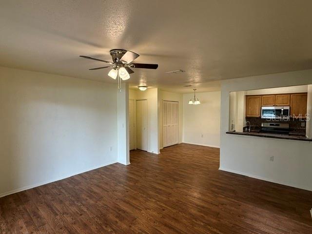 An open-concept living area features wood-look flooring, a ceiling fan, and a kitchen pass-through window — 3705 SW 27TH STREET UNIT 916, GAINESVILLE, FL