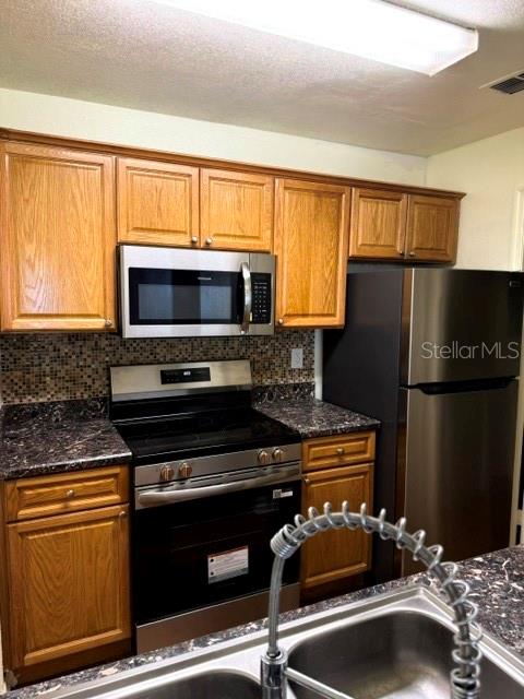 A kitchen features oak cabinets, stainless steel appliances, and a dark granite countertop — 3705 SW 27TH STREET UNIT 916, GAINESVILLE, FL