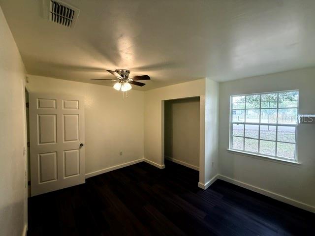 A bedroom features dark wood flooring, a ceiling fan, a white door, and a window — 3705 SW 27TH STREET UNIT 916, GAINESVILLE, FL