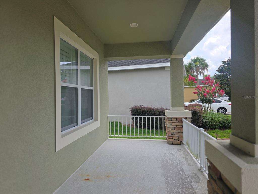 A covered porch features a concrete floor, white railings, and a stone-based support column — 17545 BUCKINGHAM GARDEN DRIVE, LITHIA, FL