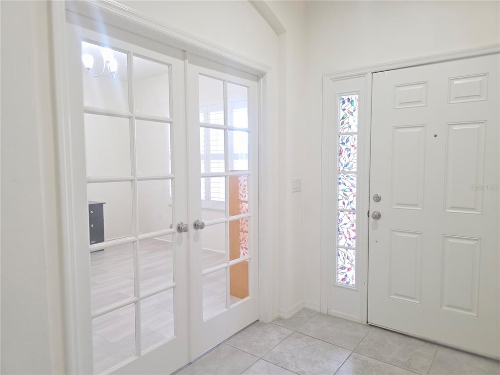 An entryway features white tile flooring, a white front door with sidelights, and French doors — 17545 BUCKINGHAM GARDEN DRIVE, LITHIA, FL