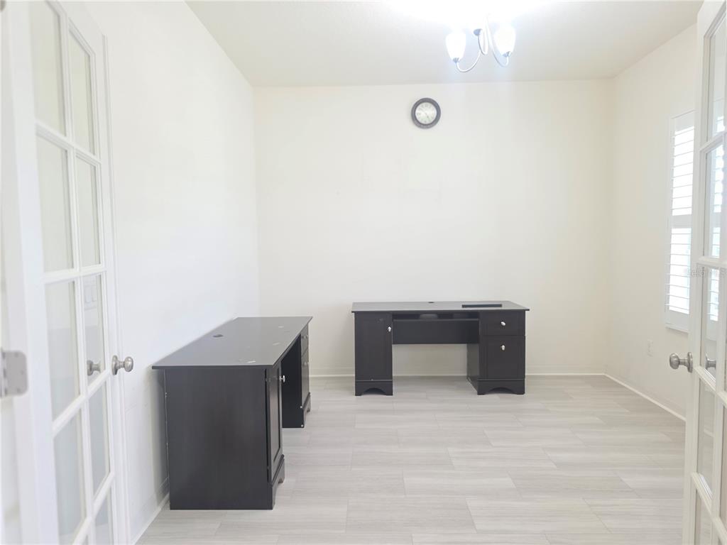 An office room with two dark wooden desks, white walls, and light-colored wood-look flooring — 17545 BUCKINGHAM GARDEN DRIVE, LITHIA, FL