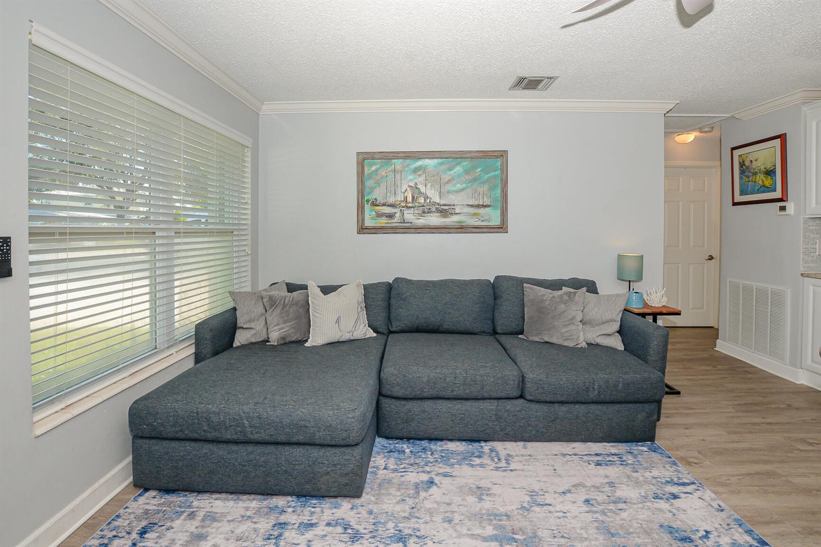 A living room features a blue sectional sofa, a patterned area rug, and wall art — 110 SW Hideaway Place, Stuart FL 34994, STUART, FL