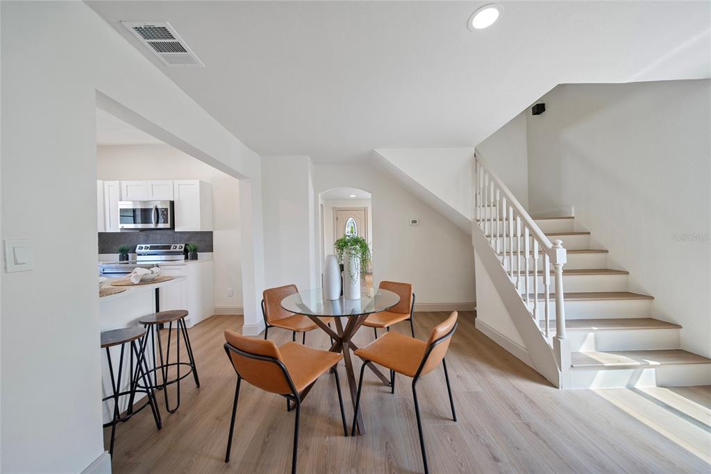 A dining area with a glass table and four chairs sits beside a wooden staircase — 2930 W ARCH STREET, TAMPA, FL