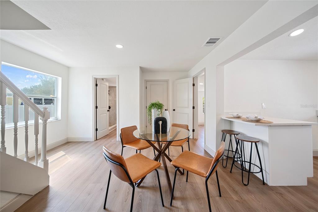 A dining area features a glass table with four chairs, light wood flooring, and a breakfast bar — 2930 W ARCH STREET, TAMPA, FL