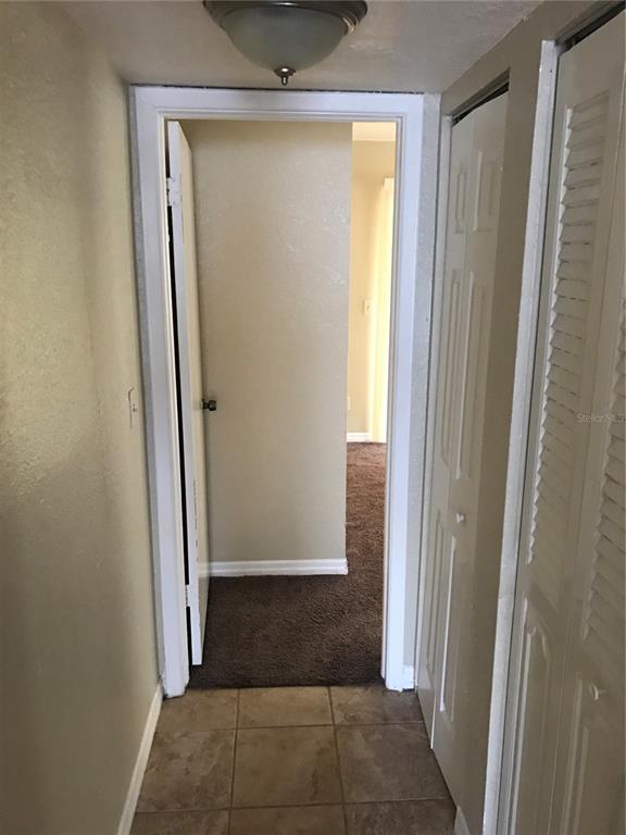 A hallway with tile flooring leads to a carpeted room through an open doorway — 7101 E BANK DRIVE UNIT 7101, TAMPA, FL