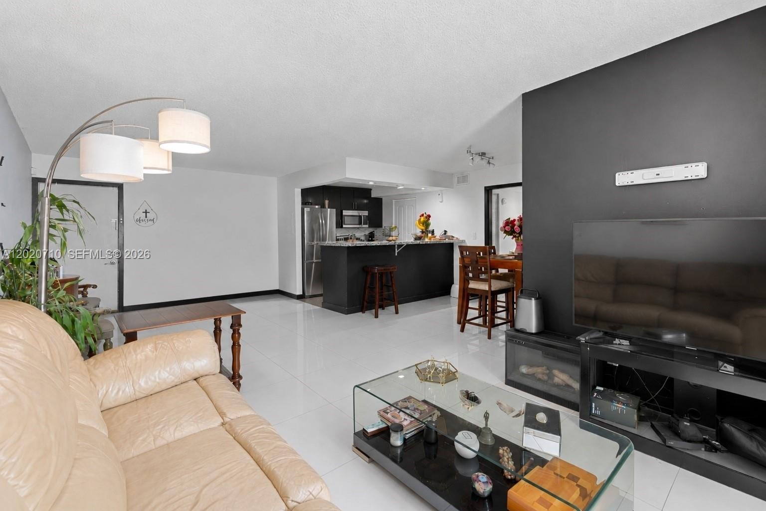 A living room with white tile floors, a black accent wall, and an open kitchen — 15430 SW 82nd Ln # 622, Miami FL 33193, MIAMI, FL
