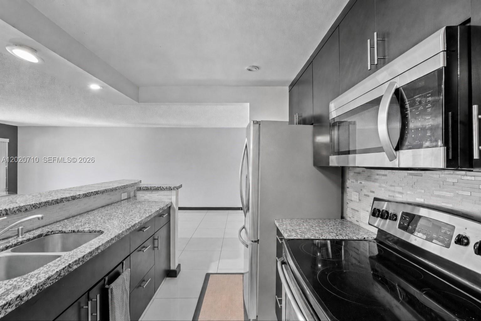 A kitchen features dark cabinets, stainless steel appliances, and granite countertops with a breakfast bar — 15430 SW 82nd Ln # 622, Miami FL 33193, MIAMI, FL