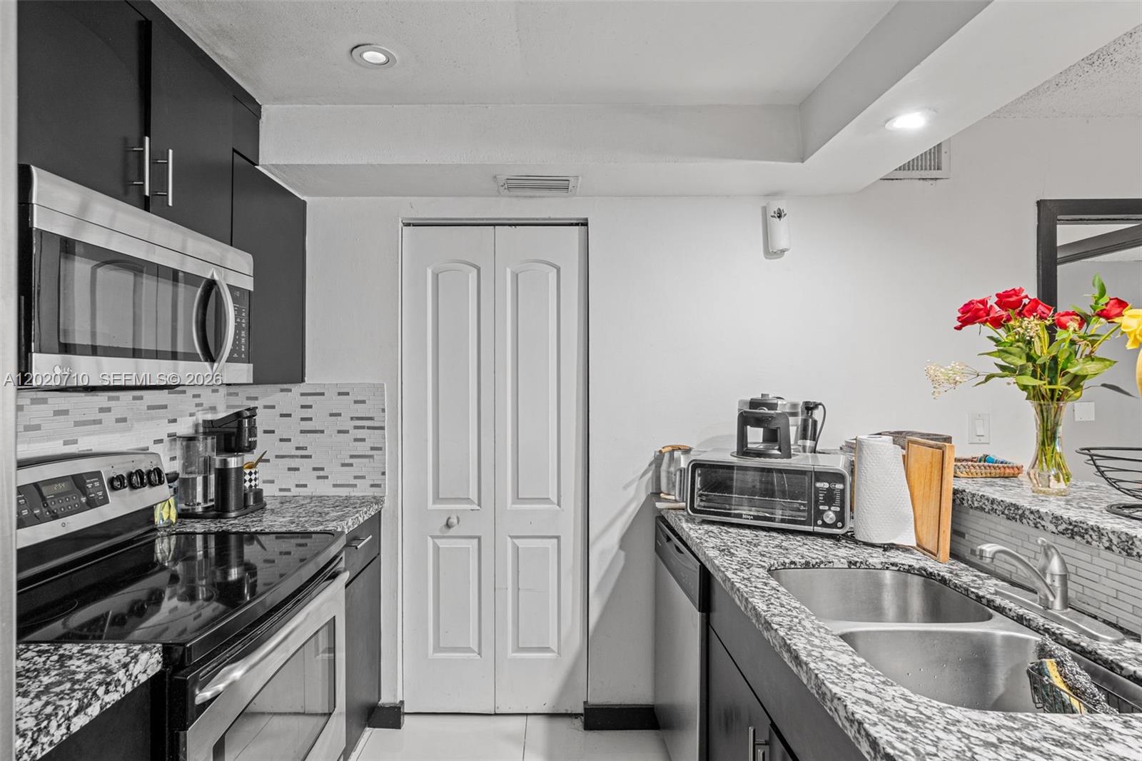 A kitchen features dark cabinets, granite countertops, a stainless steel microwave, and a white door — 15430 SW 82nd Ln # 622, Miami FL 33193, MIAMI, FL