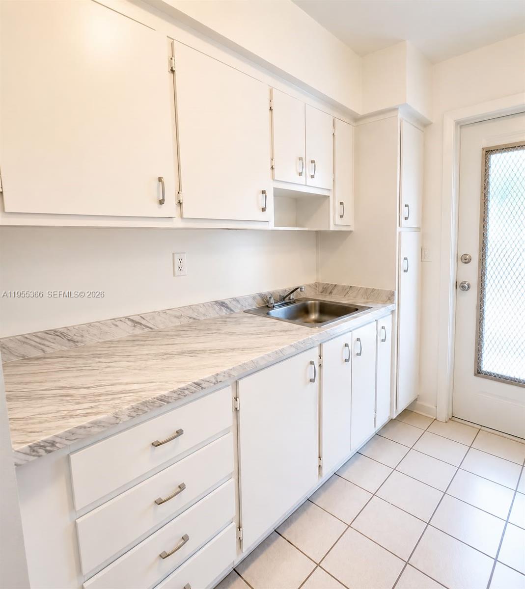 A kitchen features white cabinets, a marble-patterned countertop, a stainless steel sink, and tiled flooring — 12655 NE 16th Ave # 16, North Miami FL 33161, NORTH MIAMI, FL
