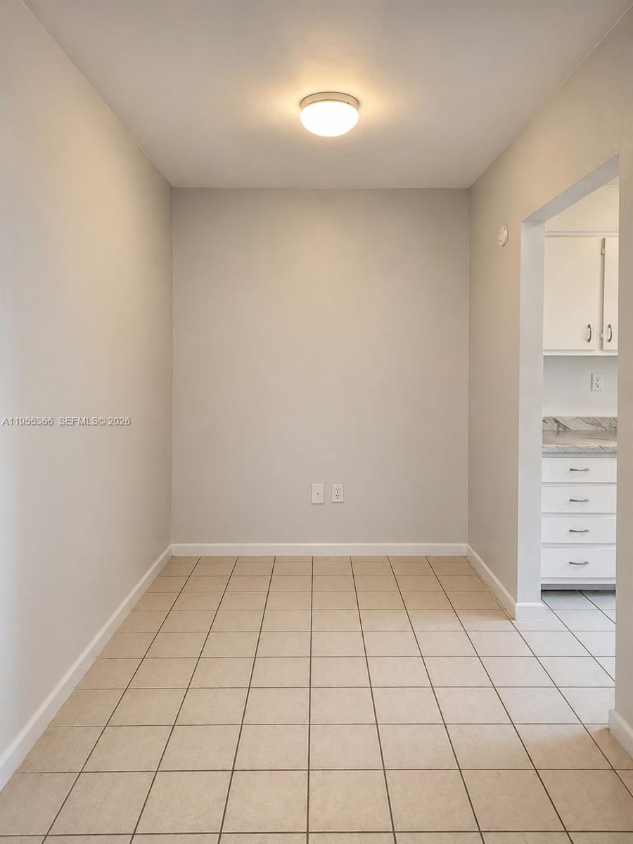 This is a small, empty dining area with beige tile flooring and light gray walls — 12655 NE 16th Ave # 16, North Miami FL 33161, NORTH MIAMI, FL