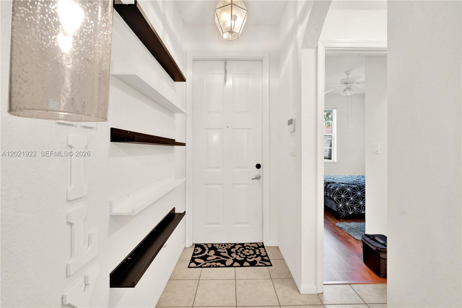An entryway features a white door, tiled floor, and wall-mounted shelves with dark accents — 18730 SW 25th Ct, Miramar FL 33029, MIRAMAR, FL