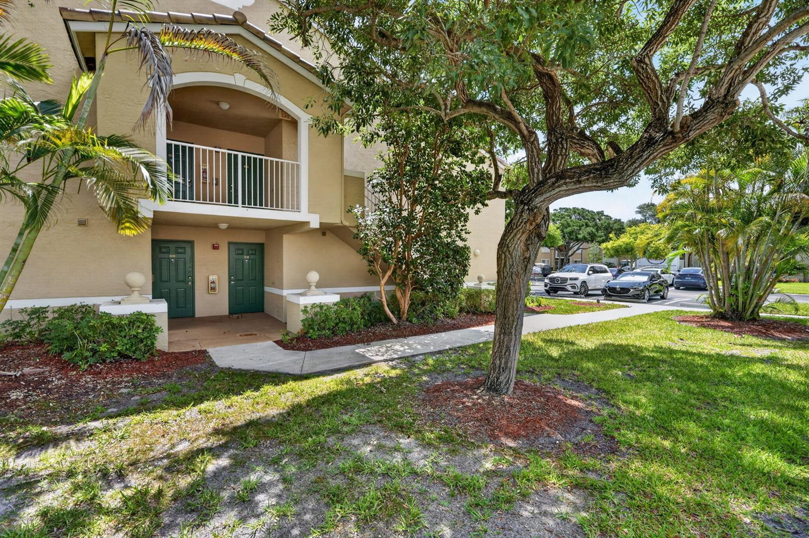 An exterior view of a two-story apartment building with green doors and a balcony — 236 Village Boulevard # 1202, Tequesta FL 33469, TEQUESTA, FL