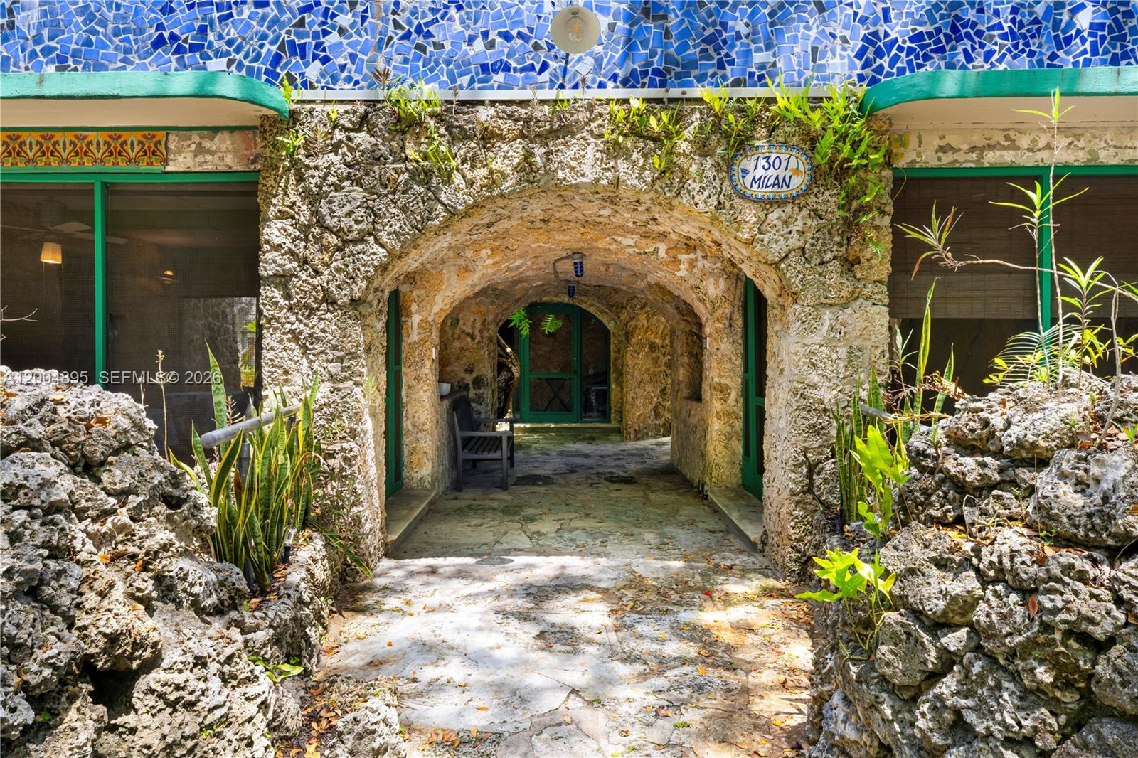 A stone archway leads to a covered entrance with a blue mosaic tile facade — 1301 Milan Ave, Coral Gables FL 33134, CORAL GABLES, FL