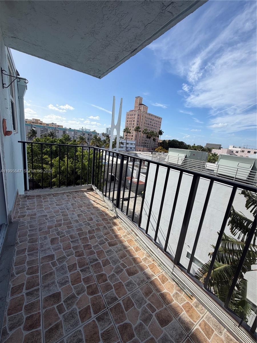 A balcony with tiled flooring and a black metal railing overlooks a city street — 720 Collins Ave # 506, Miami Beach FL 33139, MIAMI BEACH, FL