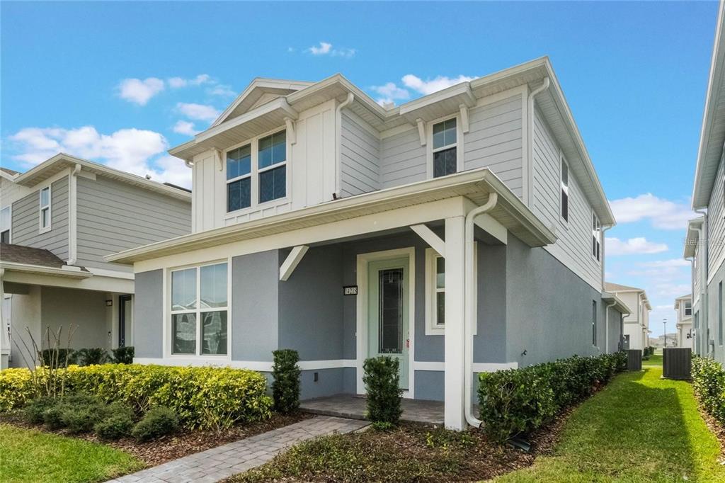 A two-story house with gray stucco, white horizontal siding, and a covered front porch — 14218 LANIKAI BEACH DRIVE, ORLANDO, FL