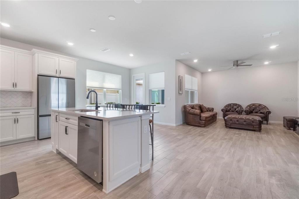 A kitchen with white cabinets and a center island opens into a living area — 14218 LANIKAI BEACH DRIVE, ORLANDO, FL