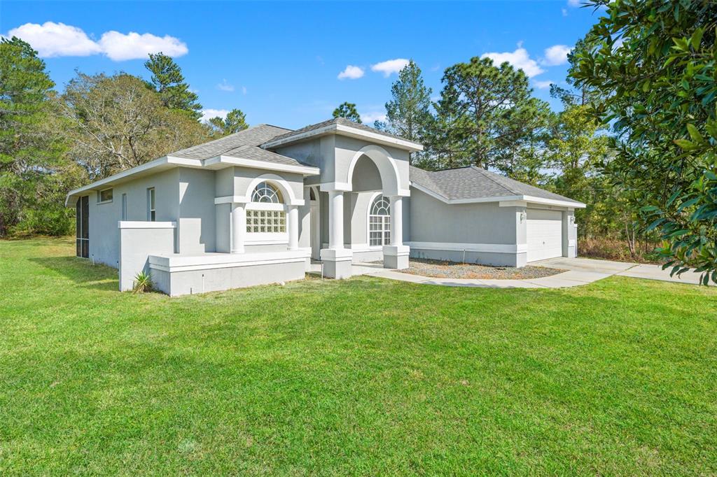 A single-story gray house with a prominent arched entryway and a two-car garage — 11128 LOMITA WREN ROAD, WEEKI WACHEE, FL
