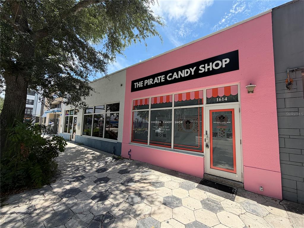 A pink storefront with a black sign reading The Pirate Candy Shop on a sidewalk — 1610 CENTRAL AVENUE, ST PETERSBURG, FL