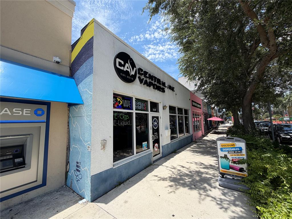 A storefront for a vape shop with a blue awning and a sidewalk sign — 1610 CENTRAL AVENUE, ST PETERSBURG, FL