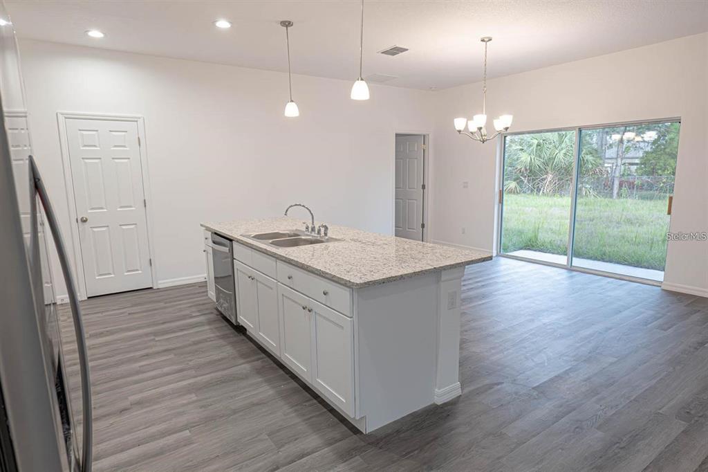 A kitchen island with a granite countertop sits in a room with gray wood flooring — 561 WILDMER ROAD SW, PALM BAY, FL