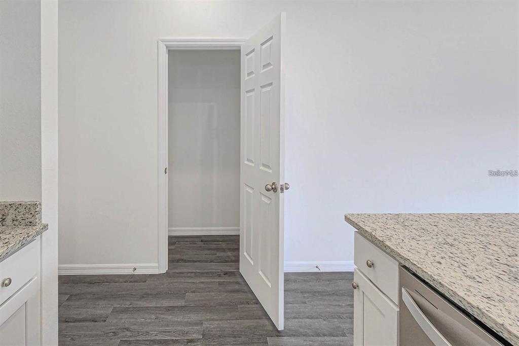 A white door opens to a small room with gray wood-look flooring and white walls — 561 WILDMER ROAD SW, PALM BAY, FL