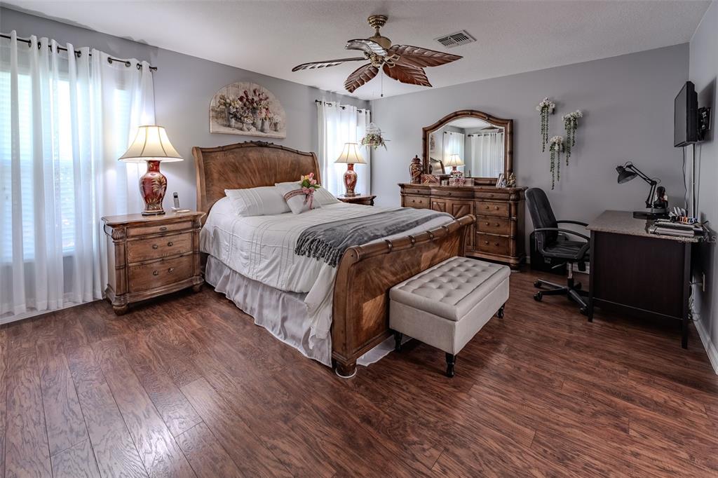 A bedroom features a wooden sleigh bed, matching dresser, desk, and wood-look flooring — 1708 SW 155TH PLACE ROAD, OCALA, FL