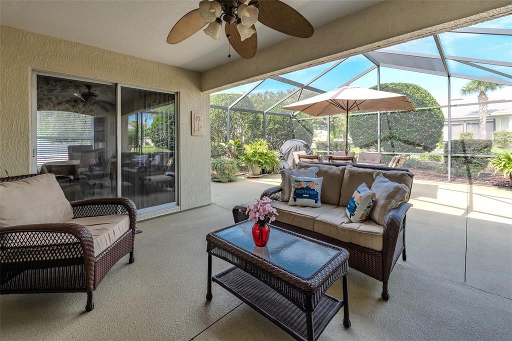 A covered patio features wicker furniture, a glass-top coffee table, and a screened-in outdoor area — 1708 SW 155TH PLACE ROAD, OCALA, FL