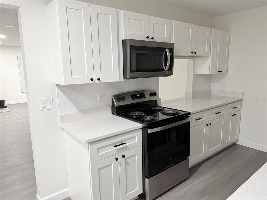 A kitchen features white cabinets, stainless steel appliances, and light-colored countertops — 6266 YORKTOWN DRIVE UNIT 179, ORLANDO, FL