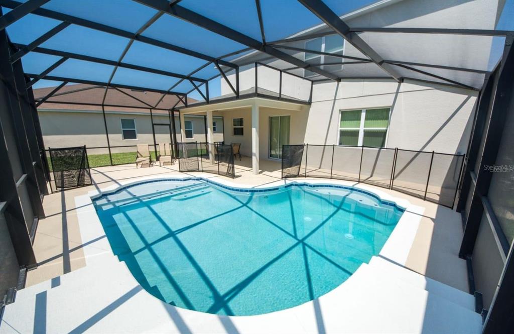 A screened-in patio features a swimming pool with a safety fence and a covered lanai — 4748 BLUE DIAMOND STREET, KISSIMMEE, FL