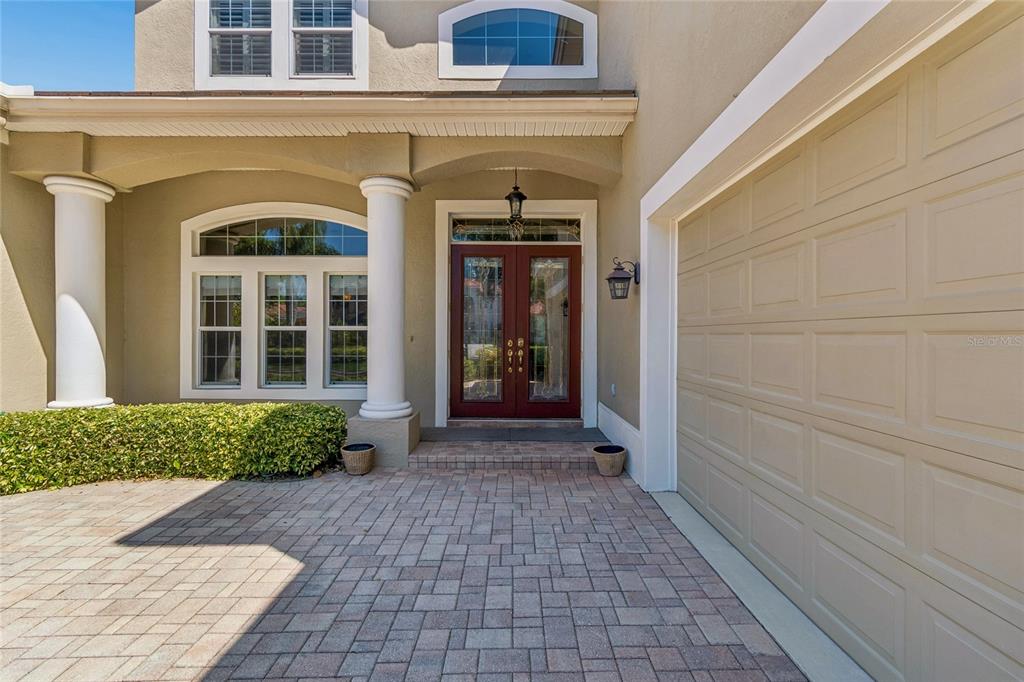 The exterior of a house features a brick paver driveway, double front doors, and columns — 601 VIENTO DE AVILA, TAMPA, FL