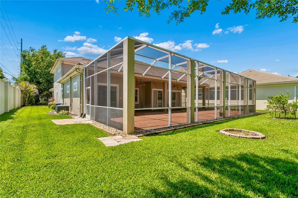 A backyard view of a house with a large screened-in patio and green lawn — 601 VIENTO DE AVILA, TAMPA, FL