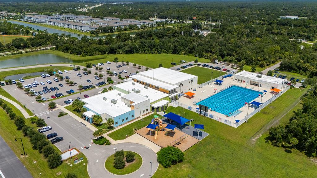 An aerial view of a community center featuring a swimming pool, playground, and parking lot — 1968 SUNSET PRESERVE WAY, PORT CHARLOTTE, FL