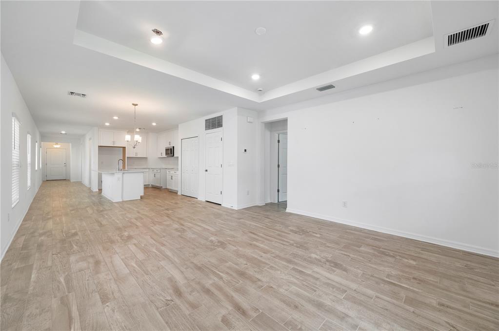 An open-concept living area with white walls, recessed lighting, and light wood-look tile flooring — 1968 SUNSET PRESERVE WAY, PORT CHARLOTTE, FL