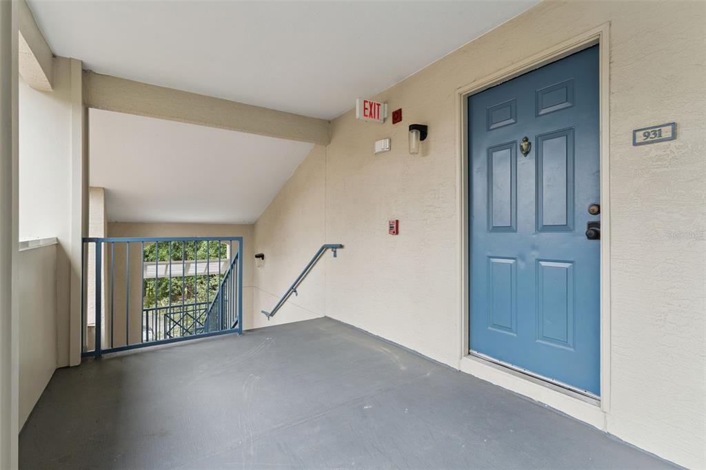 An exterior apartment landing features a blue door numbered 931, a staircase, and metal railings — 7270 WESTPOINTE BOULEVARD UNIT 931, ORLANDO, FL