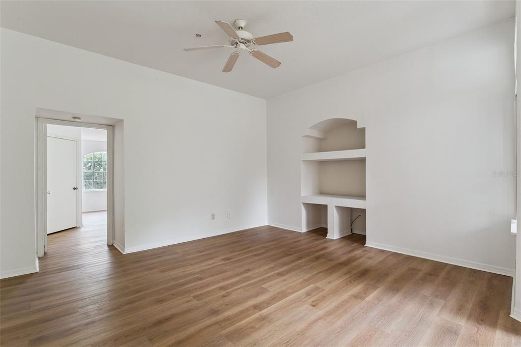 An empty room with wood-look flooring, a ceiling fan, and a built-in arched wall niche — 7270 WESTPOINTE BOULEVARD UNIT 931, ORLANDO, FL