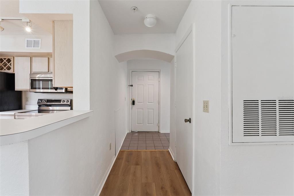 A view from a kitchen counter looking toward an entryway with wood-look flooring — 7270 WESTPOINTE BOULEVARD UNIT 931, ORLANDO, FL
