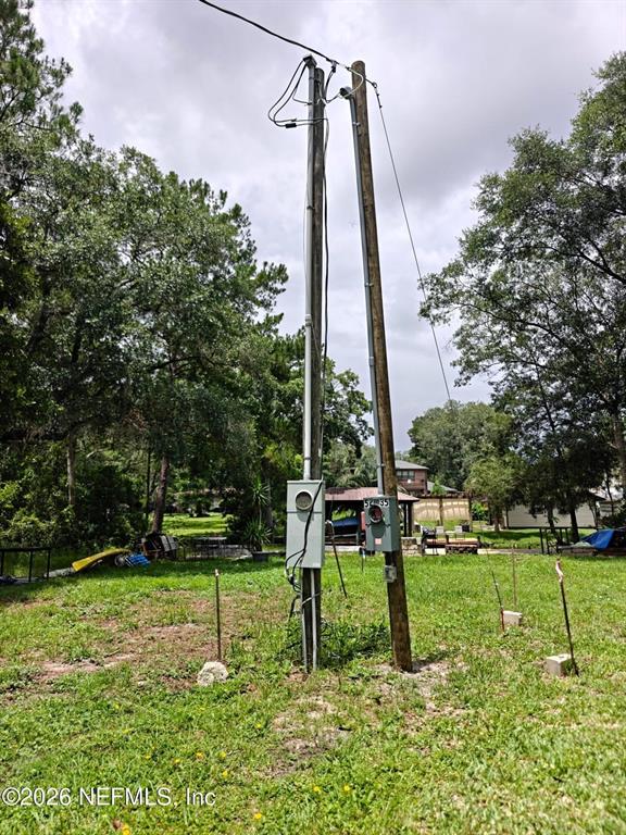 Two utility poles stand in a grassy yard with electrical meters and conduit attached — 0 HIDE-A-WAY DRIVE, JACKSONVILLE, FL