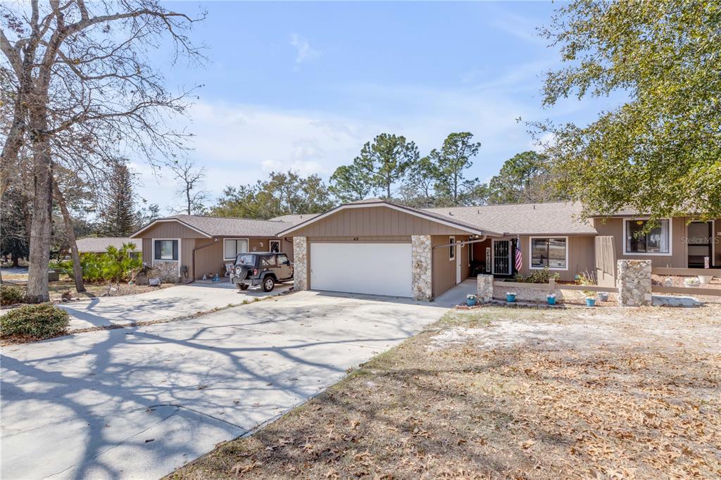 A single-story house with a two-car garage, stone accents, and a concrete driveway — 49 CROOKED PINE ROAD, PORT ORANGE, FL