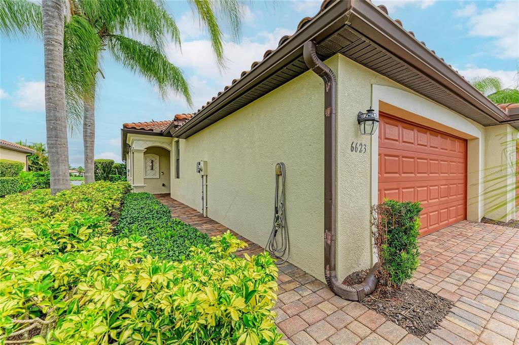 A side view of a house exterior featuring a garage, a walkway, and landscaping — 6623 CANDLESTICK DRIVE, BRADENTON, FL