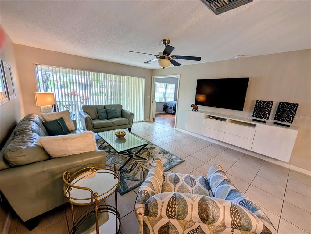 A living room features tile floors, a ceiling fan, a television, and two sofas — 6896 W COUNTRY CLUB LANE UNIT 148, SARASOTA, FL