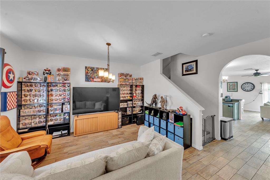 A living room features a large television, extensive collectible shelving, and tile flooring — 1939 GREENWOOD VALLEY DRIVE, PLANT CITY, FL