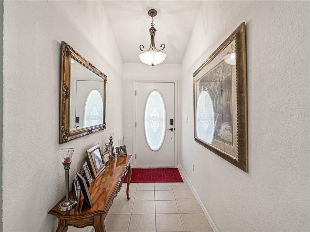 A tiled entryway features a console table, a mirror, wall art, and a front door — 11404 TURTLE DOVE PLACE, NEW PORT RICHEY, FL