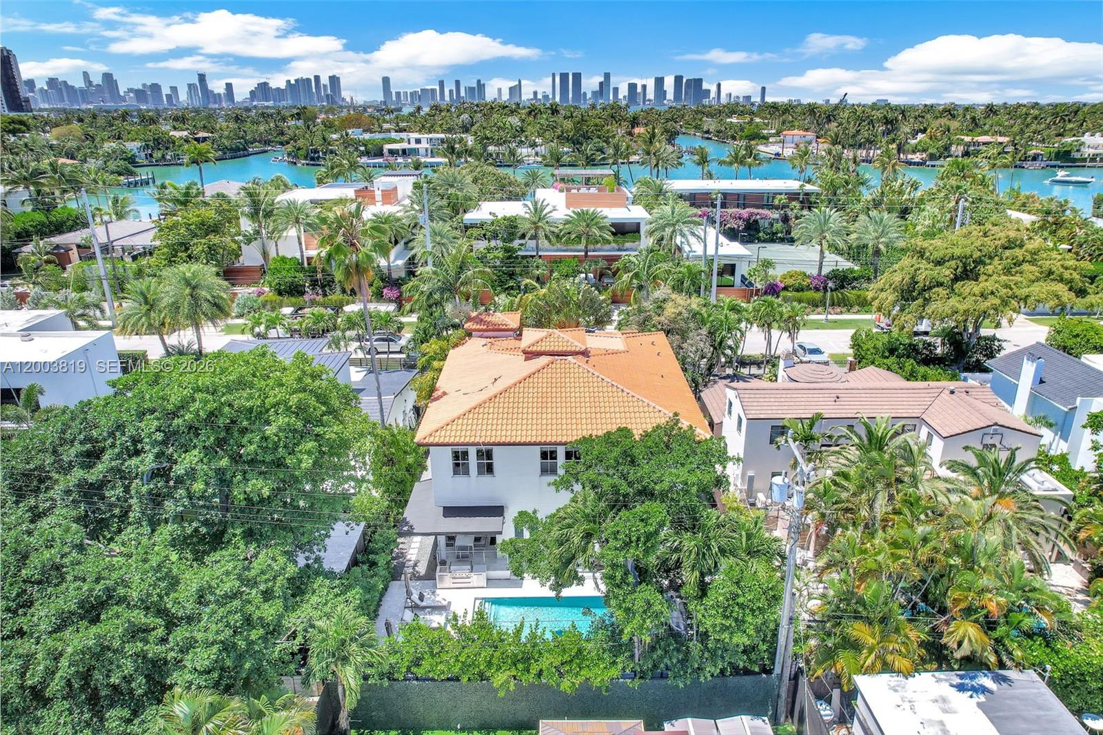 An aerial view shows a white house with a terracotta roof, pool, and surrounding trees — 2143 N Bay Rd, Miami Beach FL 33140, MIAMI BEACH, FL