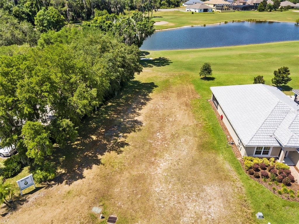 An aerial view shows a vacant residential lot situated between a wooded area and a house — Lot F-20 EAGLES WAY WAY, TAVARES, FL