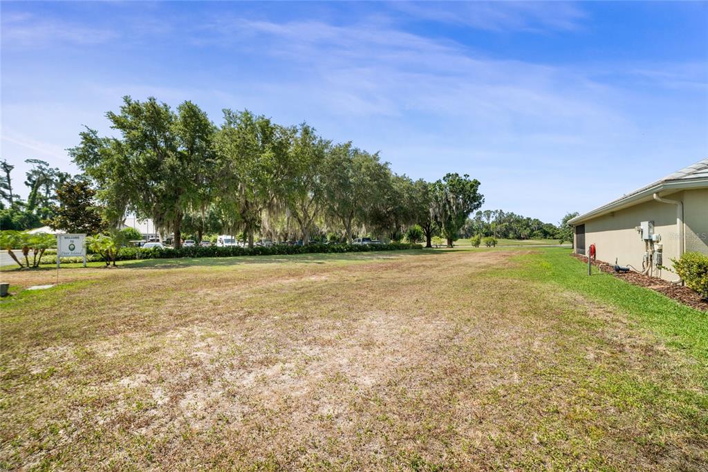 A grassy lot sits next to a house with a line of trees in the background — Lot F-20 EAGLES WAY WAY, TAVARES, FL