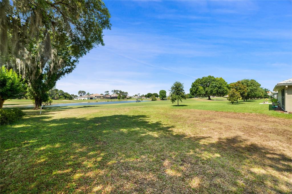 A grassy backyard overlooks a pond and golf course under a clear blue sky — Lot F-20 EAGLES WAY WAY, TAVARES, FL
