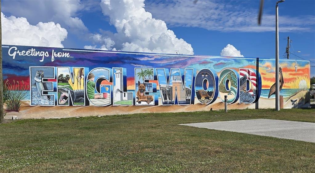 A large, colorful mural spelling ENGLEWOOD is painted on an exterior wall under a blue sky — 10 QUAILS RUN BOULEVARD UNIT 1, ENGLEWOOD, FL